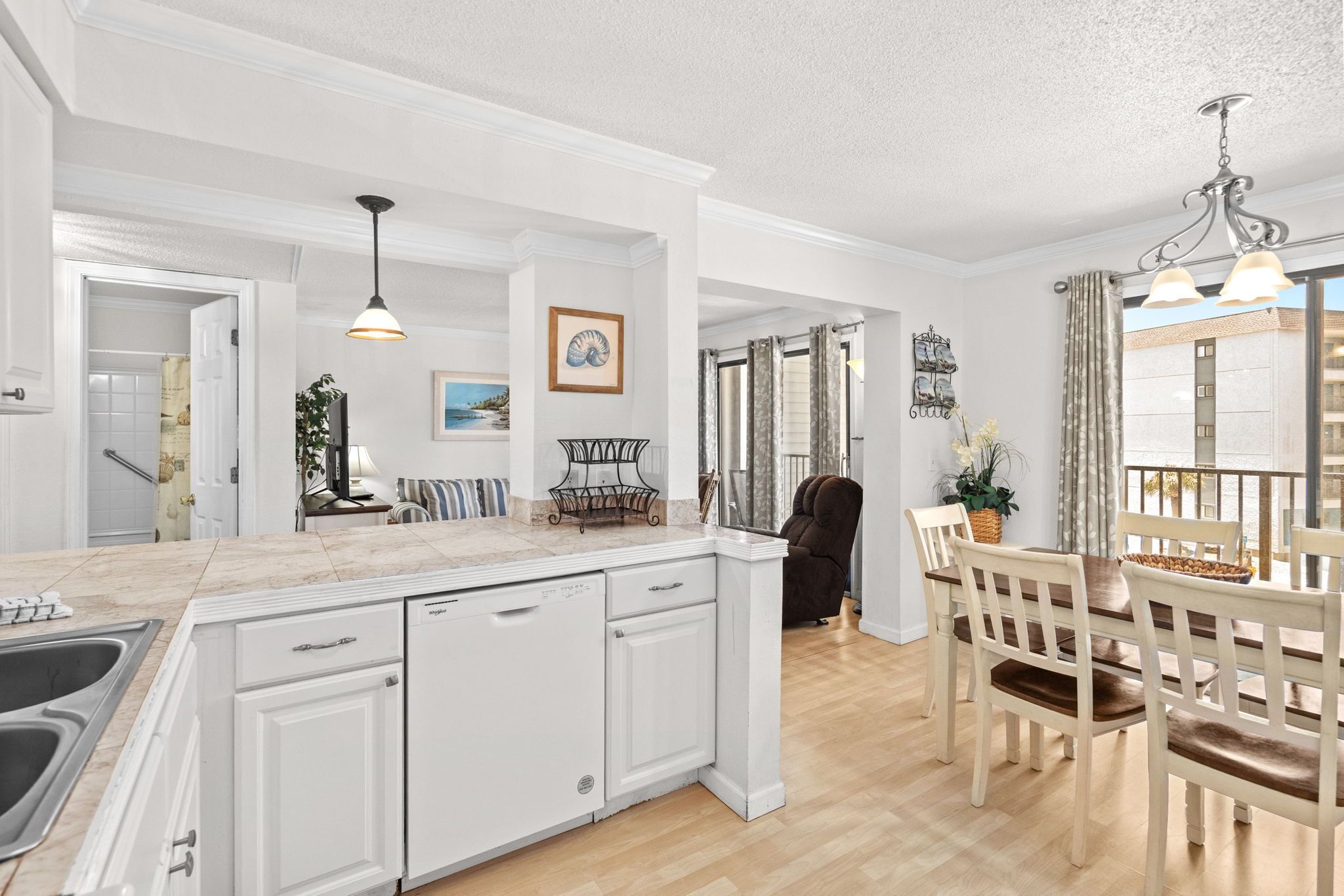 Een ruime keuken met een groot eiland, witte kasten en een eethoek met houten stoelen en een tafel.
