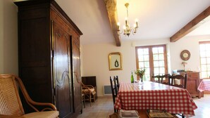 A dining area with a checkered tablecloth, wicker chairs, a wooden cabinet, and a chandelier. - House near Mont Saint Michel - Semi-detached in Lolif (Lolif)