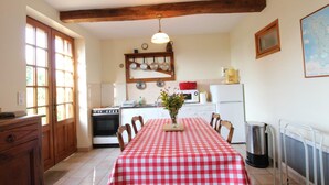 A kitchen with a red and white checkered tablecloth, wooden cabinets, a stove, and a hanging light fixture. - House near Mont Saint Michel - Semi-detached in Lolif (Lolif)