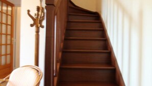 A wooden staircase with a handrail and a chair near the bottom. - House near Mont Saint Michel - Semi-detached in Lolif (Lolif)
