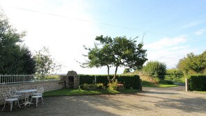 A gravel driveway leading to a stone wall with a small garden and a metal table with chairs. - House near Mont Saint Michel - Semi-detached in Lolif (Lolif)