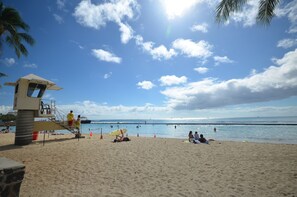 A beach with lifeguard towers, a sandy shore, and people swimming and relaxing.
