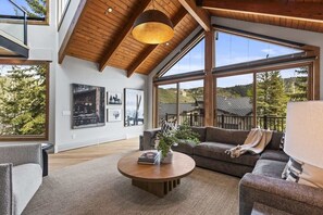 Un salon spacieux avec un haut plafond, de grandes fenêtres et une cheminée accueillante.