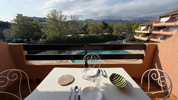 Une table dressée pour deux personnes, avec vue sur une piscine et des montagnes.