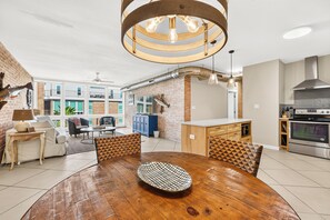 A modern kitchen with a built-in oven, a dining area with a wooden table and patterned chairs, and a brick wall with decorative fish. - This fabulous upscale condo is located right on the ship channel and in the hear (Port Aransas)