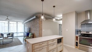 A modern kitchen with a central island, stainless steel appliances, and a brick accent wall. - This fabulous upscale condo is located right on the ship channel and in the hear (Port Aransas)