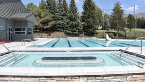 Ein Pool mit Steinrand, umgeben von Bäumen und einem Gebäude.
