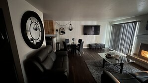 Ein modernes Wohnzimmer mit einer Couch, einem Couchtisch und einem Kamin. Es gibt einen Essbereich mit Tisch und Stühlen.