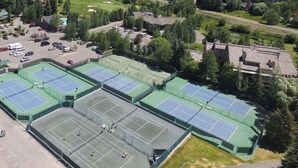 Eine Vogelperspektive auf eine Tennisanlage mit mehreren Plätzen, umgeben von Wohnhäusern und einem Parkplatz.