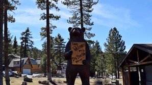 Una estatua de oso con un cartel que dice 'Louie te da la bienvenida al Lago Big Bear, California'.