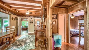 A wooden interior with a dining area, a small kitchen, and a bedroom with a bunk bed. - PRD 888 Ponderosa Cabin (New Braunfels)