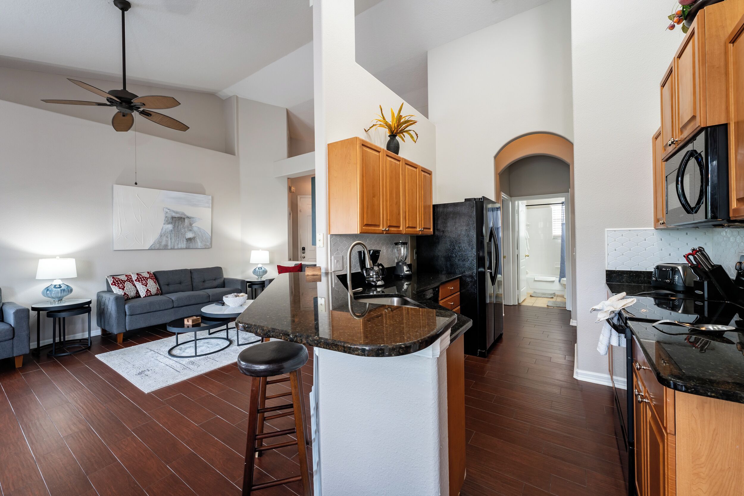 Una cocina moderna con armarios de madera, un refrigerador negro y una isla central con taburetes.