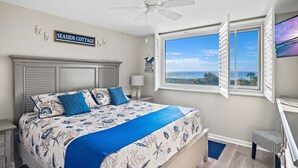 Ein Schlafzimmer mit einem Bett, einem Deckenventilator, einem Fenster mit Blick und einem Schild mit der Aufschrift 'SEASIDE COTTAGE'.