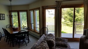 A dining area with a table and chairs, a patterned sofa, and large windows with blinds. - Ski in/out 4 BR townhome directly on Raccoon Run and the Village Chair Lift !! (Jay)