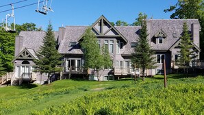 A large, two-story house with a steeply pitched roof, multiple chimneys, and a front porch. - Ski in/out 4 BR townhome directly on Raccoon Run and the Village Chair Lift !! (Jay)