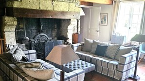 Una sala de estar acogedora con chimenea, un conjunto de sofás y una lámpara.