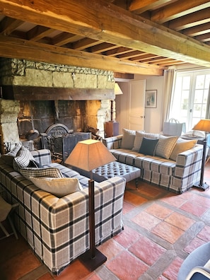 A cozy living room with a fireplace, a sofa set, and a stone wall.