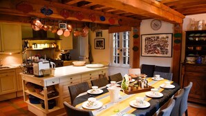 Una cocina acogedora con ollas de cobre, una mesa de comedor para cuatro personas y un techo de madera rústica.