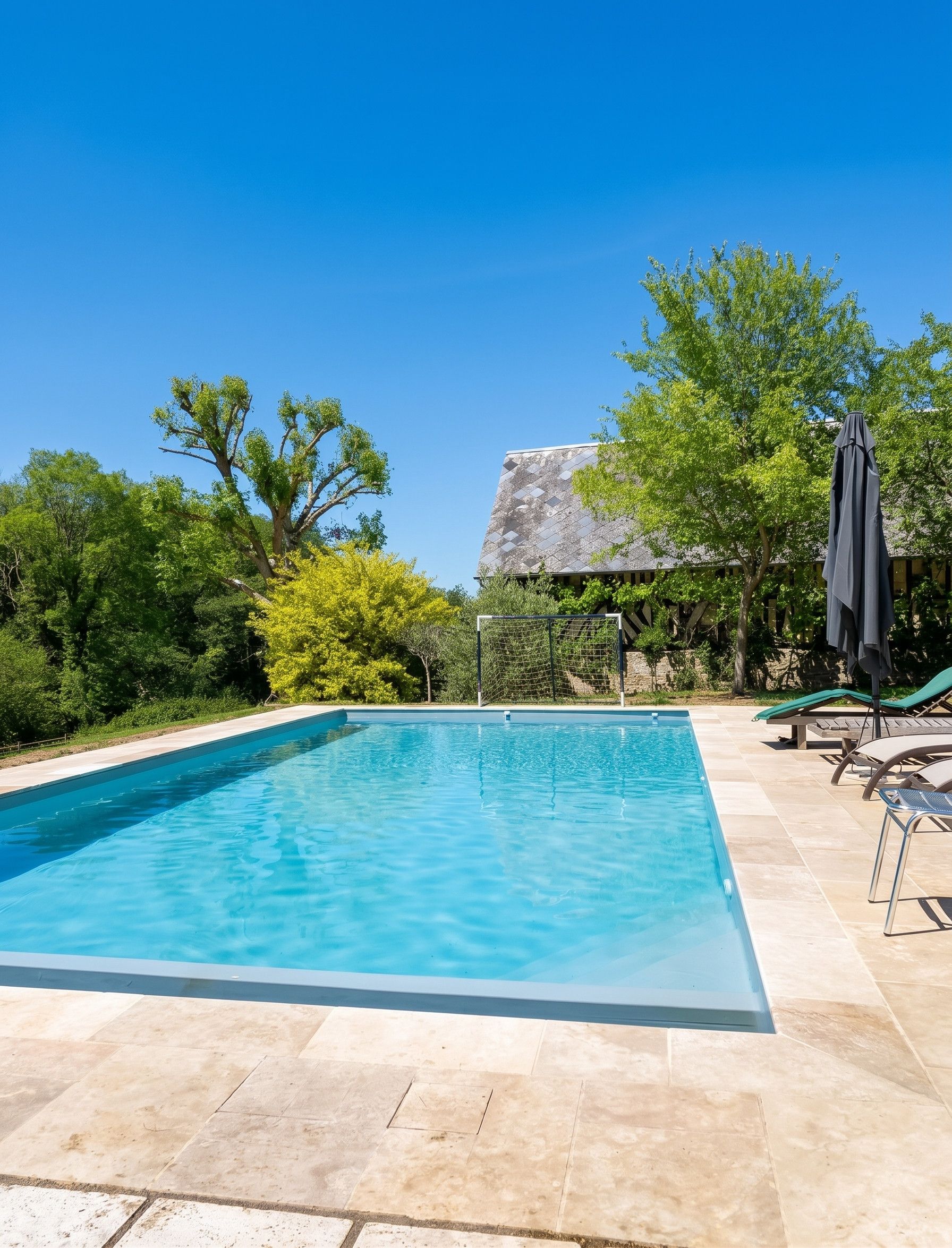 Une piscine rectangulaire à l’eau d’un bleu limpide, entourée d’une terrasse carrelée.