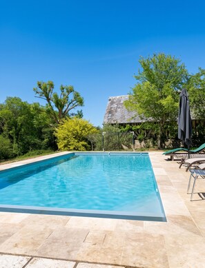 A rectangular swimming pool with a clear blue water surface, surrounded by a tiled deck.