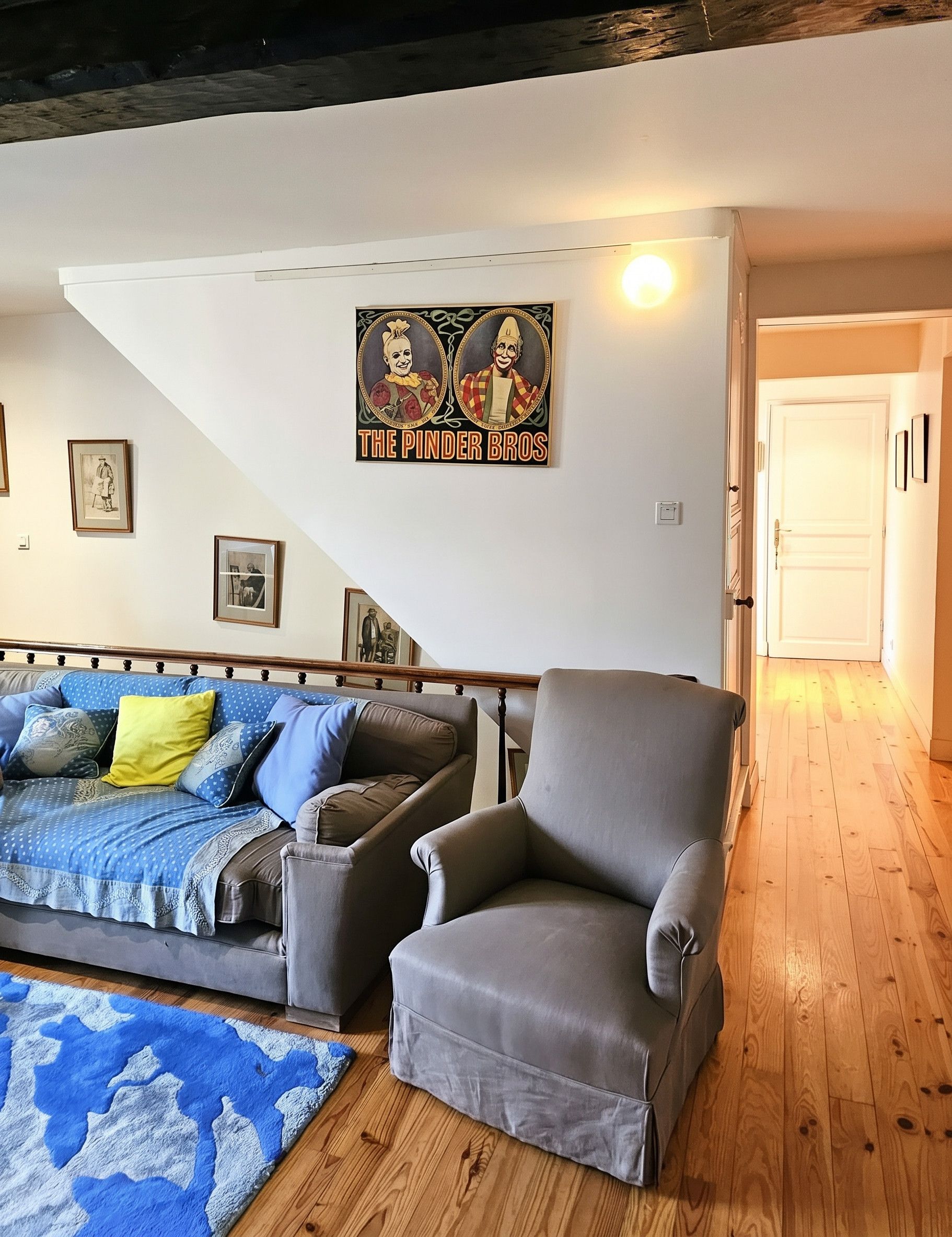 Een woonkamer met een bank, fauteuil en een poster aan de muur.