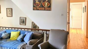 Een woonkamer met een bank, fauteuil en een poster aan de muur.