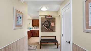 Um corredor com um banco de madeira, cozinha ao fundo e uma parede com uma pintura de peixe.