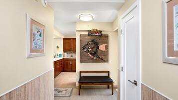 A hallway with wooden cabinets, a bench, and a wall-mounted artwork of a fish.