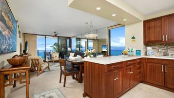 A spacious kitchen with wooden cabinets, a large island, and a view of the ocean.