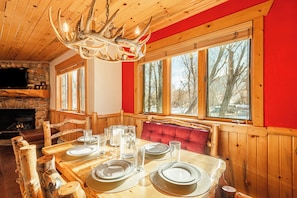 Une table à manger en bois, mise avec des assiettes, des verres et un lustre.