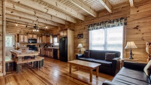 Interior de uma cabana de madeira com sala de jantar, cozinha e sala de estar.