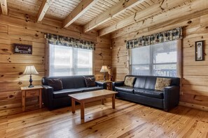 Ein Blockhaus-Interieur mit zwei Sofas, einem Holztisch und einem kleinen Beistelltisch mit Lampen.