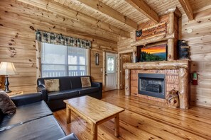 Un accogliente interno di una baita in legno con camino, divano e televisione.