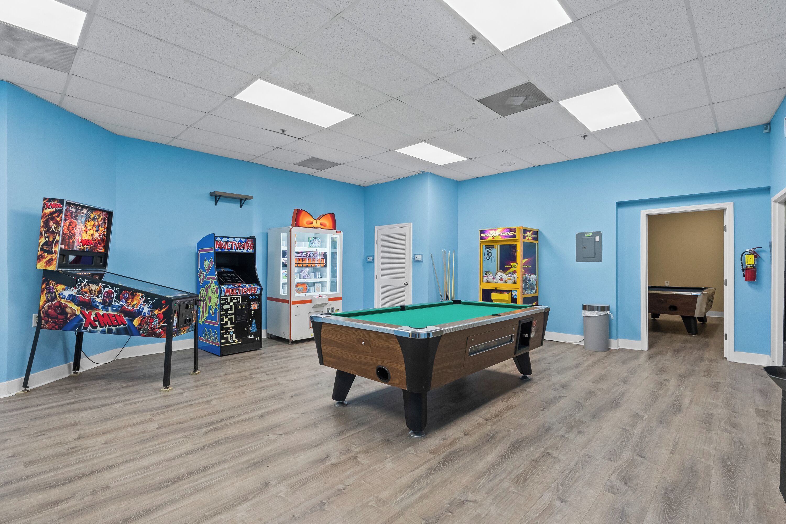 Ein Zimmer mit Billardtisch, Spielautomaten und einer Tür zu einem weiteren Raum.