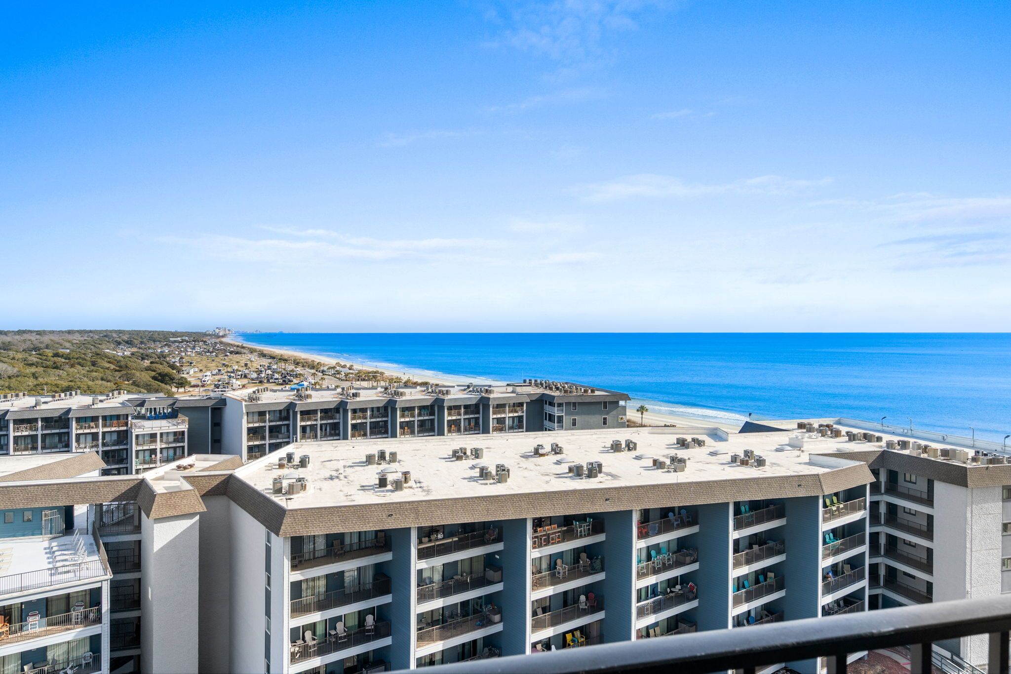 A high-rise hotel with multiple balconies overlooking a beach and ocean.
