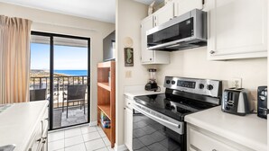 Een keuken met uitzicht op zee, een balkon met een stoel en een eethoek.