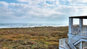 Une vue sur la côte avec un bâtiment blanc doté d’un balcon et d’un escalier.