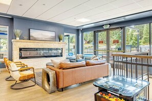 Un salon moderne doté d’une cheminée, de sièges confortables et offrant une vue sur la piscine.