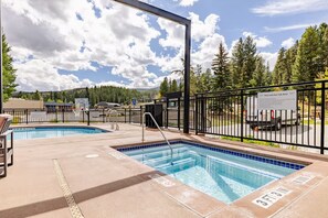 A pool area with two pools, a fenced walkway, and a sign indicating a pool and hot tub area. - Ski-In/Ski-Out Penthouse | 3BR, Sleeps 10 | Main St | Pool & Hot Tubs (Breckenridge)