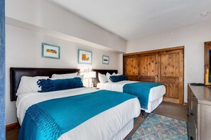 Une chambre d’hôtel avec deux lits, une armoire en bois, un bureau et un téléviseur.