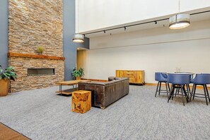 A lobby with a stone wall, a wooden reception desk, a leather sofa, and a round table with chairs. - Ski-In/Ski-Out Penthouse | 3BR, Sleeps 10 | Main St | Pool & Hot Tubs (Breckenridge)