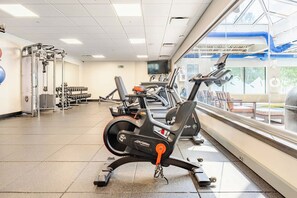 A gym with cardio machines, weightlifting equipment, and a large window with a view of the outdoors. - Ski-In/Ski-Out Penthouse | 3BR, Sleeps 10 | Main St | Pool & Hot Tubs (Breckenridge)
