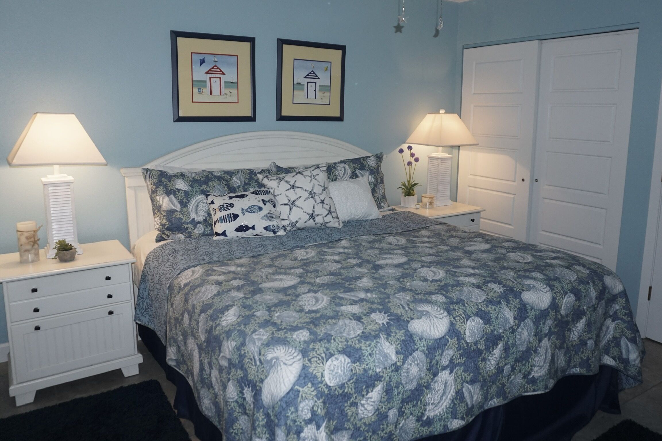 Une chambre à coucher comprenant un lit, deux tables de chevet, une commode et deux tableaux encadrés accrochés au mur.