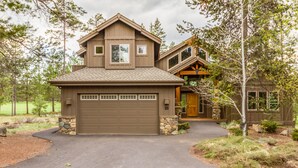 A two-story house with a garage, stone foundation, and a well-maintained driveway. - Spacious 5BR for 12: Hot Tub, A/C, Foosball + Ping Pong, North Sunriver-BIGL18 (Sunriver)