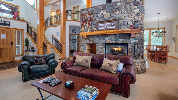 A spacious living area with a stone fireplace, leather sofas, and a wooden staircase. - Spacious 5BR for 12: Hot Tub, A/C, Foosball + Ping Pong, North Sunriver-BIGL18 (Sunriver)