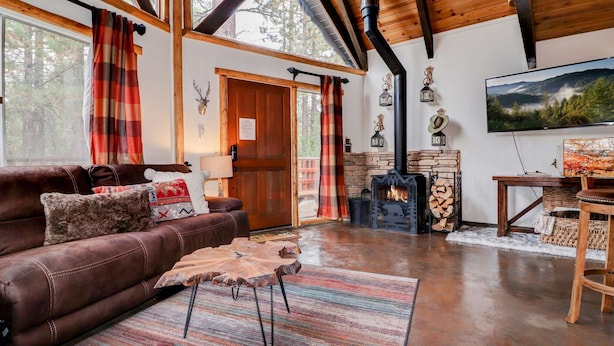 A cozy living room with a leather sofa, a coffee table, a fireplace, and a television.