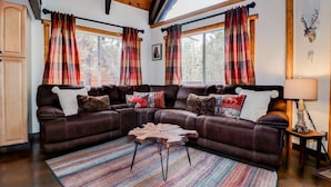 A cozy living room with a sectional sofa, a wooden coffee table, and plaid curtains.