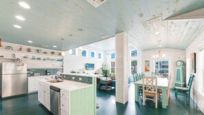 A spacious kitchen with a central island, white cabinetry, and a dining area with a wooden table and chairs. - Come and play at our Blue Hawaiian Beach house! Close to the beach! The perfect (Port Aransas)