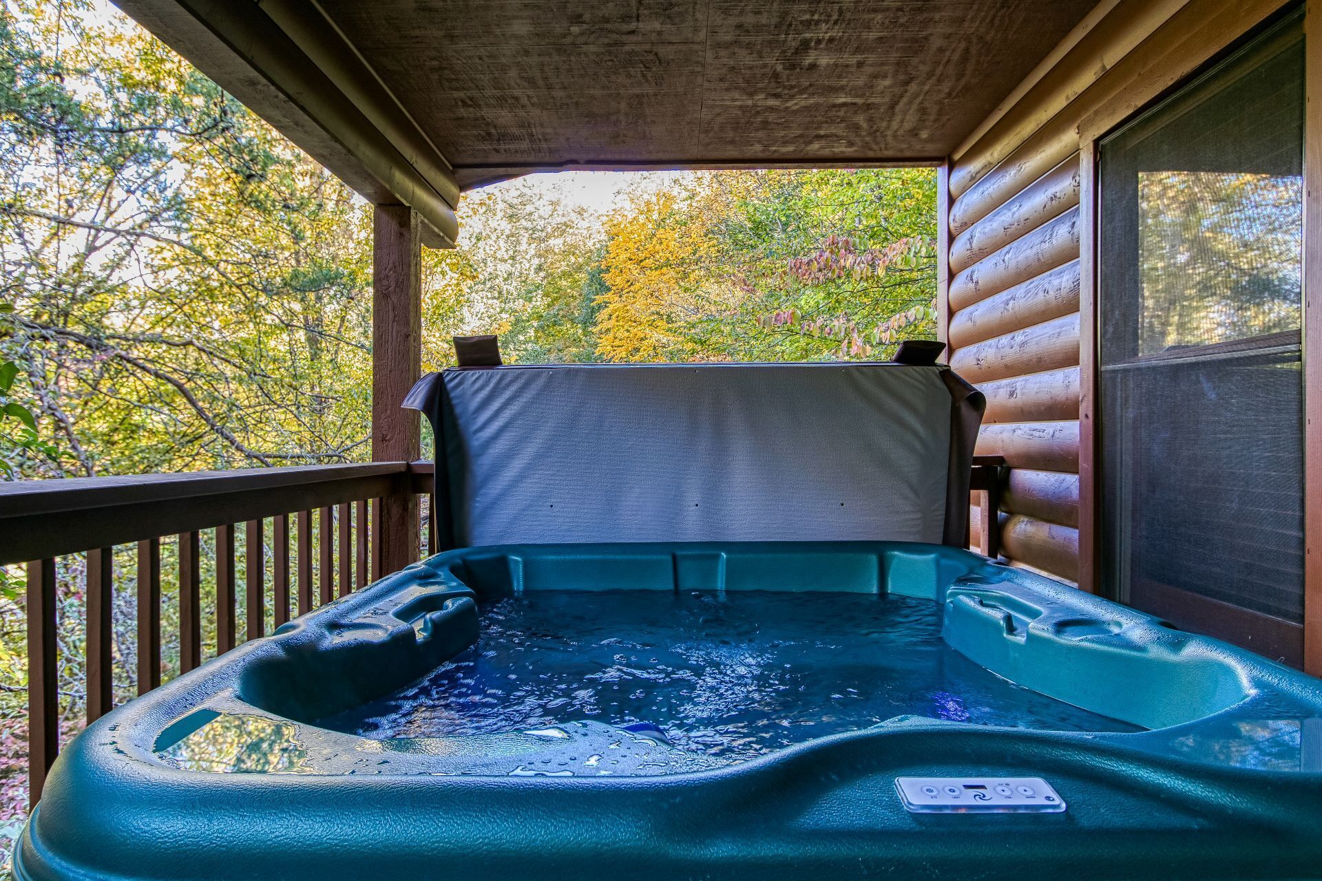 A hot tub on a wooden deck with a view of autumn trees.