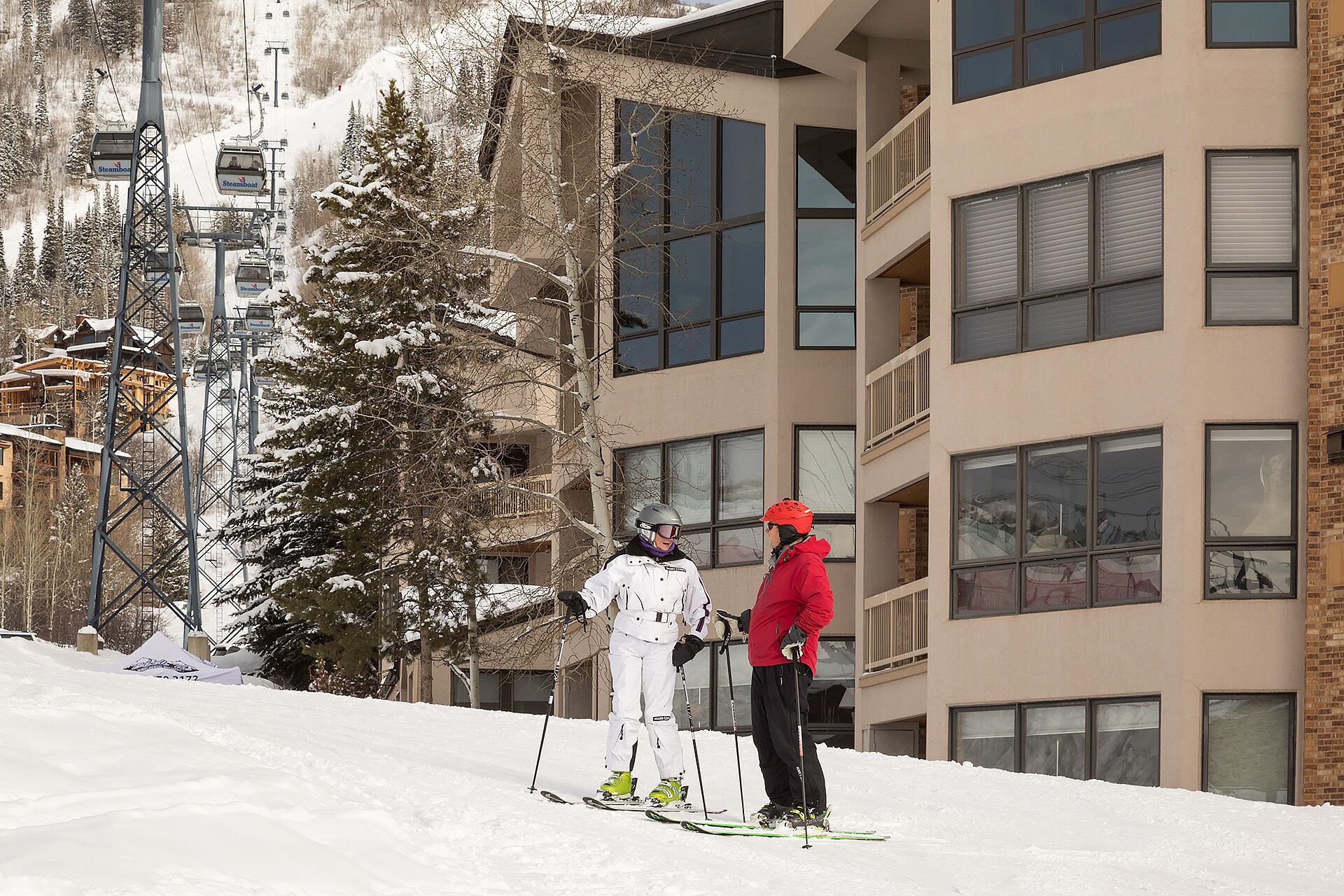 A ski resort with a ski lift, a building with multiple windows, and a snow-covered landscape.